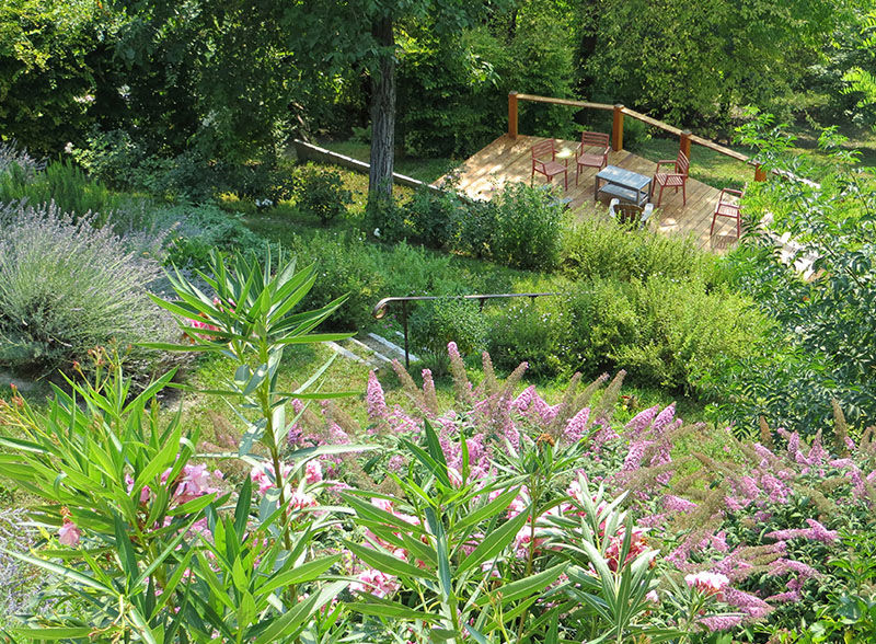 Giardino di campagna informale: la terrazza di design risalta tra la vegetazione.<br /><br />